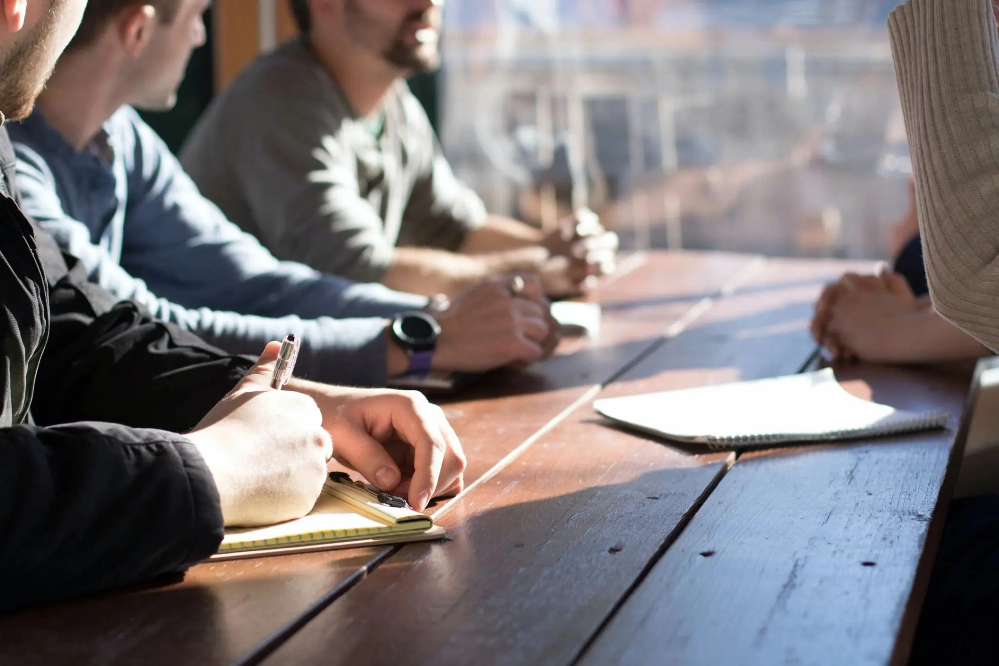 People sitting at a table, taking notes.