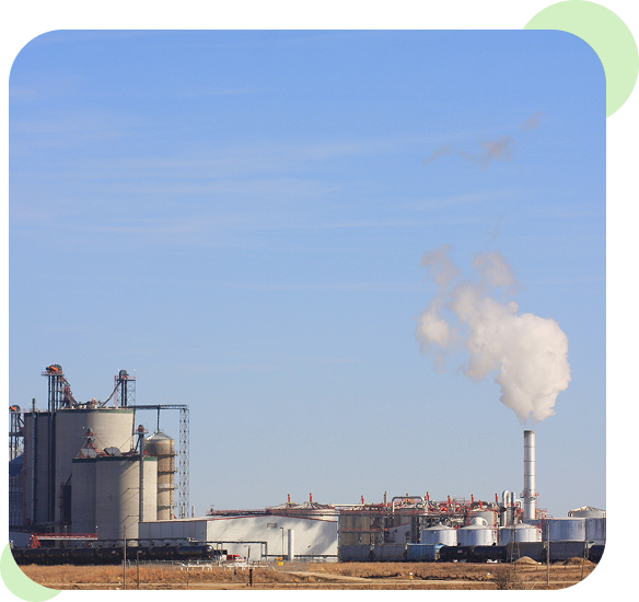 Industrial plant emitting smoke under a clear blue sky.