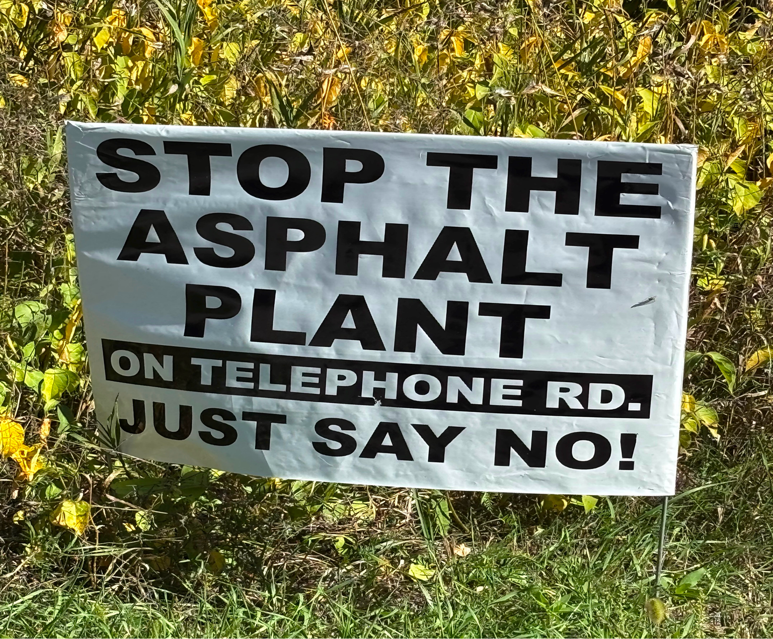 Sign urging to stop the asphalt plant with a call to say no on telephone.