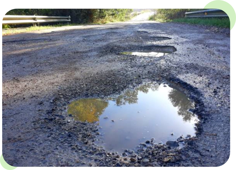 A pothole filled with water on a cracked road.