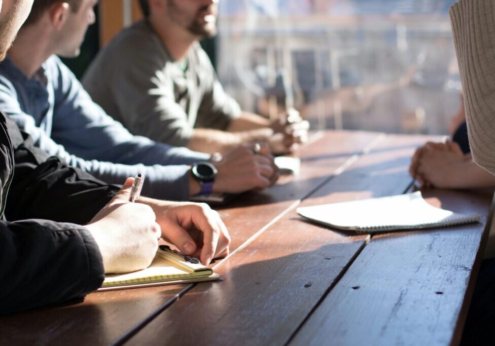 People sitting at a table, taking notes.