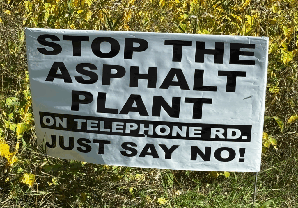 Sign urging to stop the asphalt plant with a call to say no on telephone.